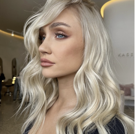 Wavy long blonde hair styled to the side, featuring the Platinum Blonde Service by blonde hairdresser in Melbourne.